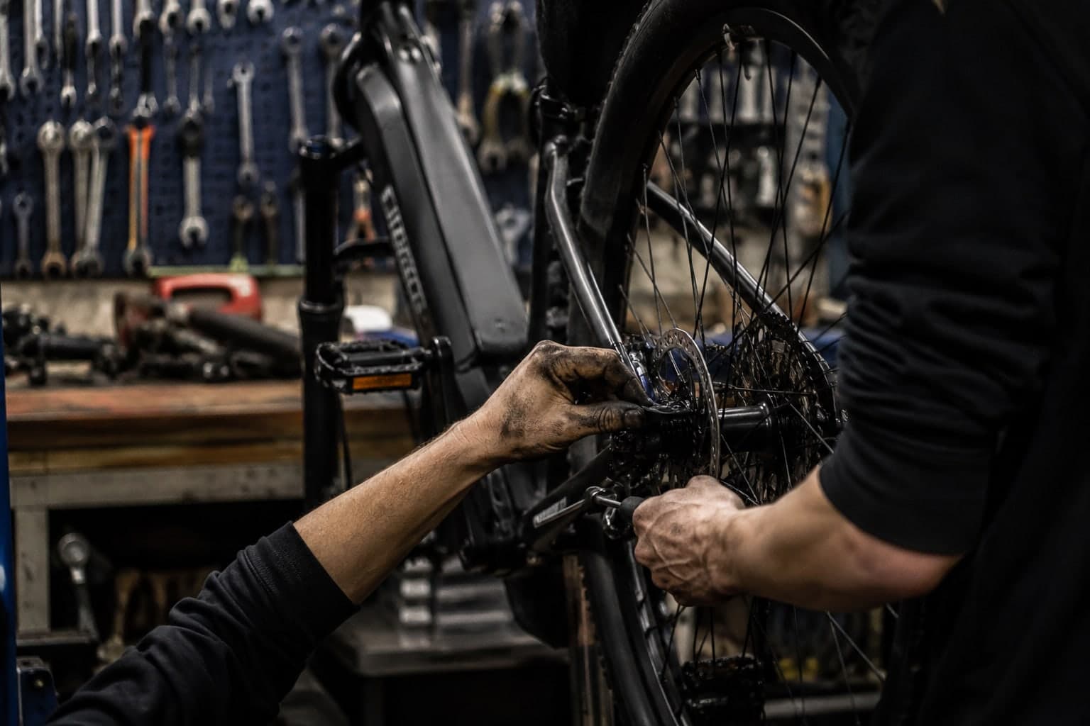 Meccanico al lavoro sulla ruota di una e-bike in officina